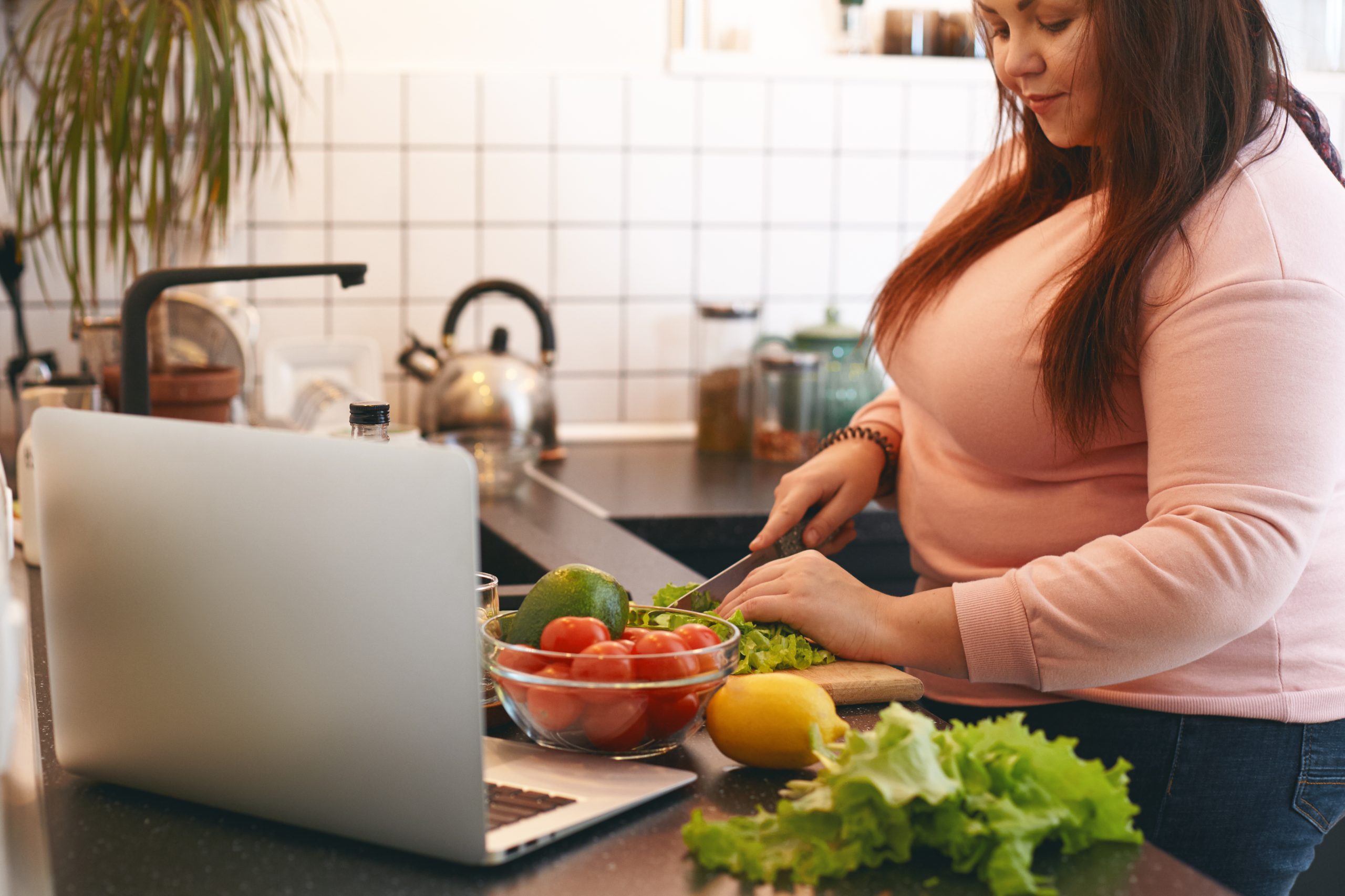 Woman preparing a healthy avocado and lettuce salad at home as part of weight management