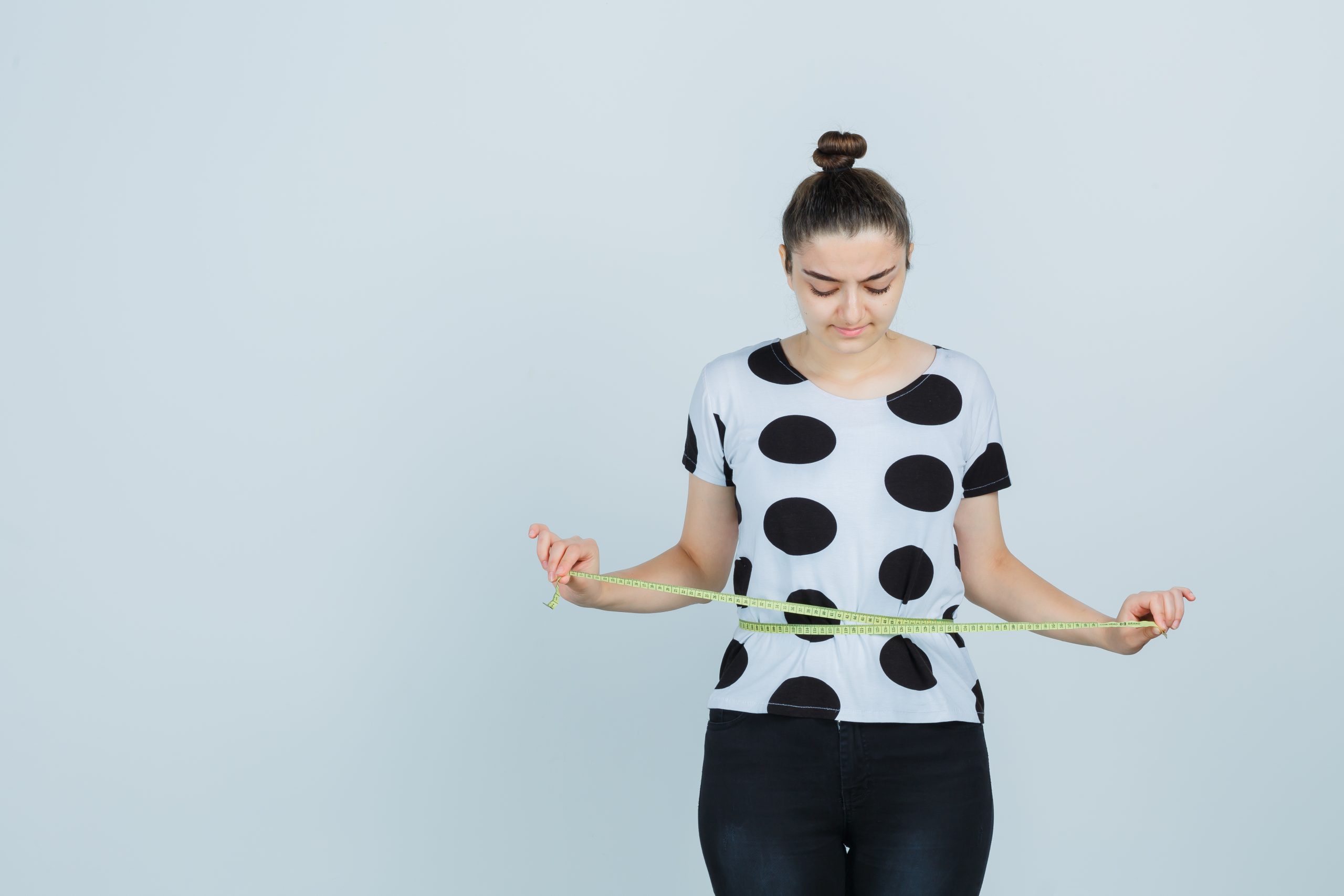 Woman measuring her waist as part of a weight loss plan