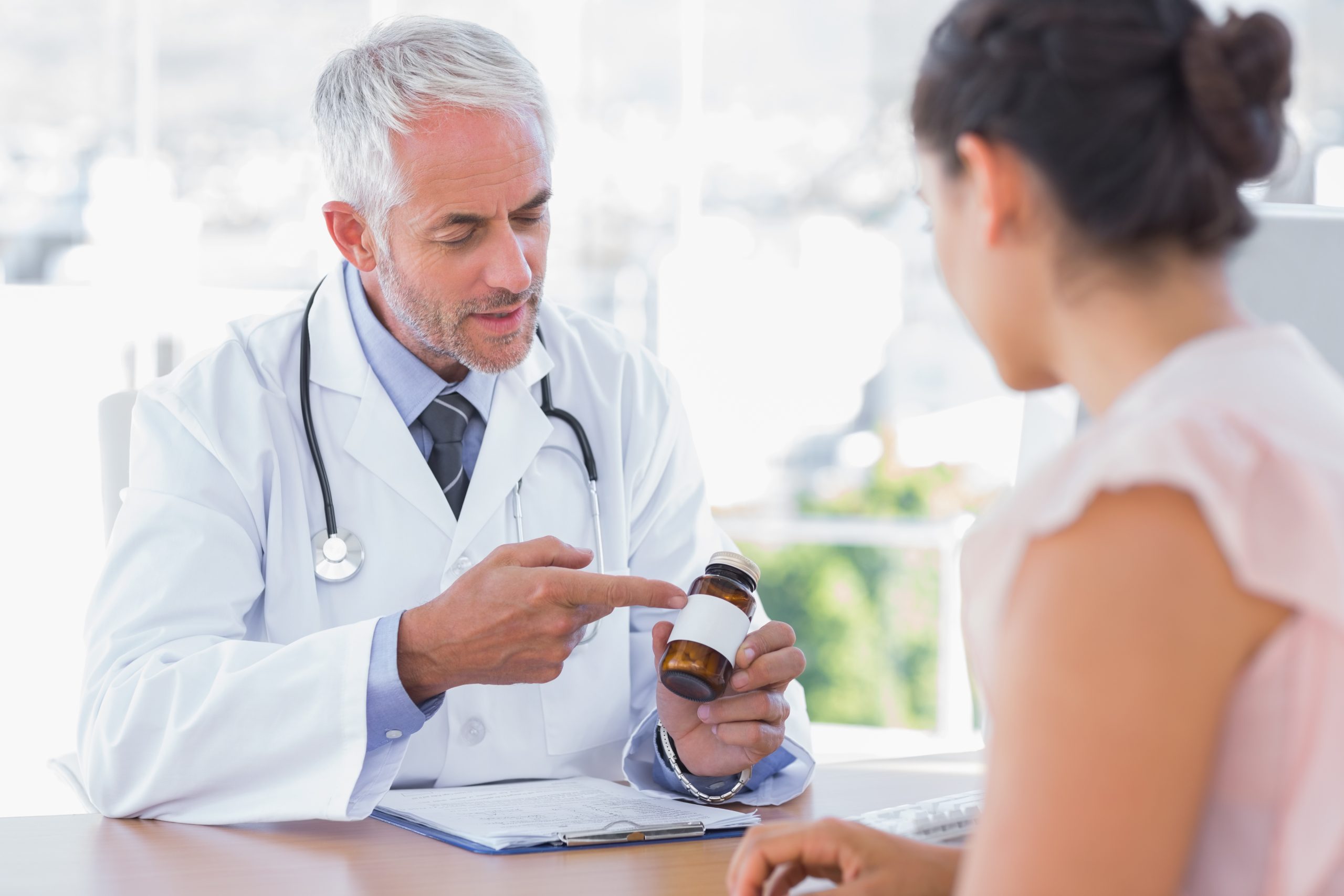 Doctor explaining the bottle of pills to patient in the office at desk What is Phentermine?