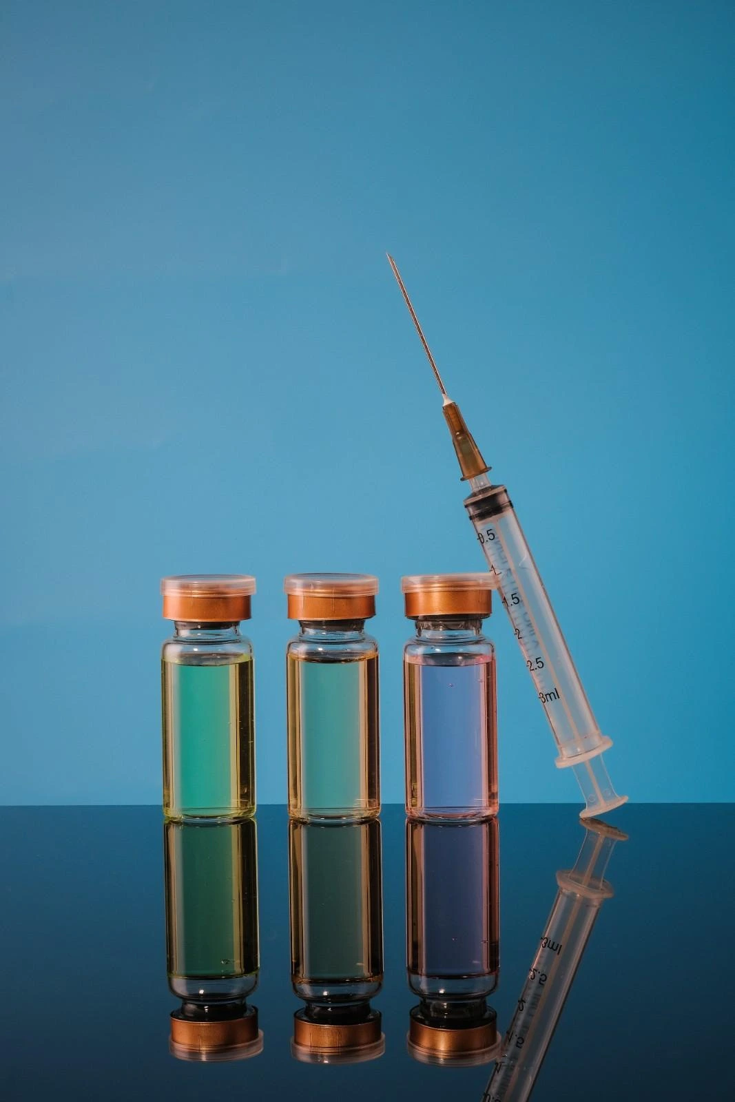 Close-up of two vials, one with clear and one with yellow liquid, labeled for lipotropic MIC and B12 injections.